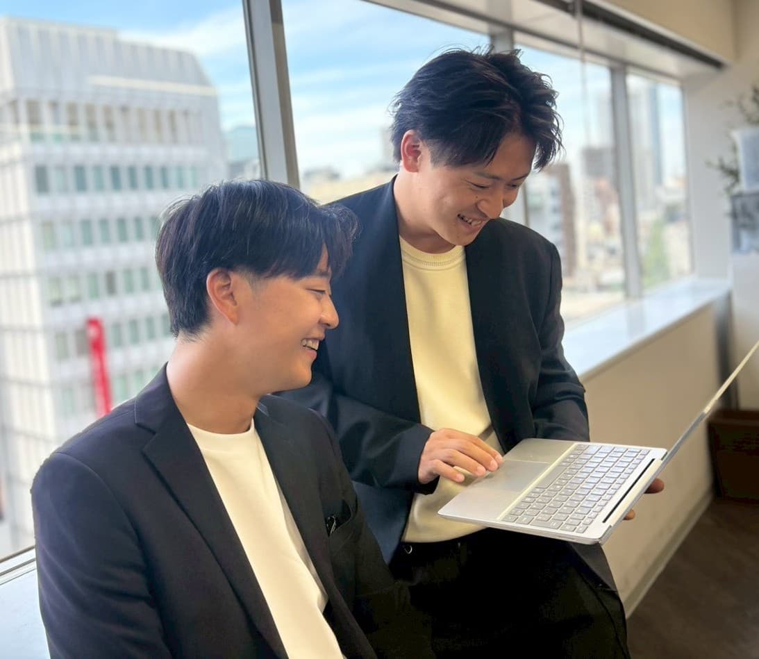 BE INTERNのメンバーがノートパソコンを見ながら会話している様子